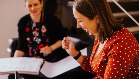 2 women smilling looking at documents