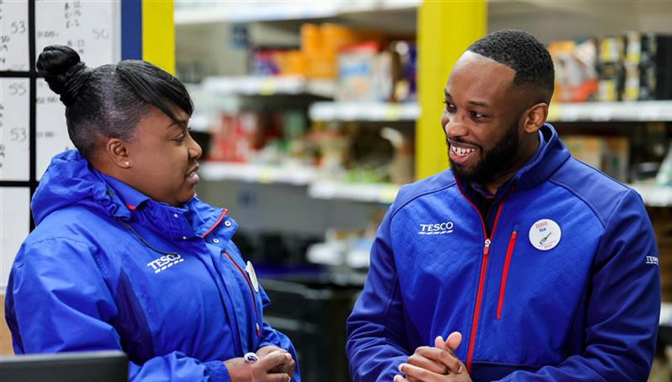 A customer being served at a till. the customer and till operator are smiling at eachother