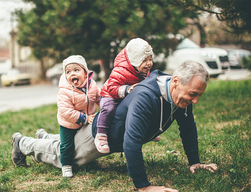 Man doing press-up with young kids sitting on him