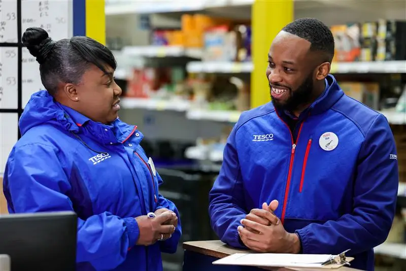 A customer being served at a till. the customer and till operator are smiling at eachother